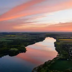 Zachód słońca nad Nysą Kłodzką maluje niebo odcieniami różu i pomarańczu, odbijając się w spokojnej tafli wody.