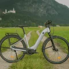 Szary rower elektryczny na tle zamku i gór. Czy rower elektryczny trzeba rejestrować? Zależy od jego mocy i prędkości.