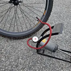Pompka rowerowa z manometrem obok koła. Sprawdź ciśnienie w oponach rowerowych, tabela pomoże Ci dobrać odpowiednie.