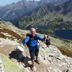 Uśmiechnięty turysta na kozi wierch trasie, z kciukiem w górze. W tle piękne Tatry i dwa jeziora.