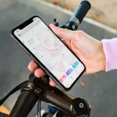 Aplikacja na rower iPhone pokazuje mapę z zaznaczonymi punktami. Użytkownik planuje trasę lub szuka miejsc.