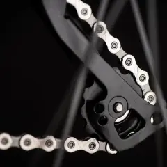Zbliżenie na rowerowy napęd, gdzie widać mechanizm przerzutki i fragment łańcucha. Dowiedz się, jak liczyć ogniwa w łańcuchu, by zapewnić płynną jazdę.