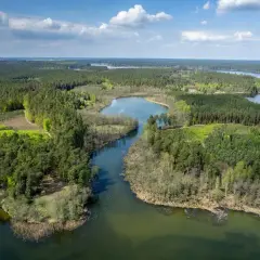 Malownicze pojezierze brodnickie z licznymi jeziorami i lasami, gdzie woda odbija błękitne niebo z chmurami.