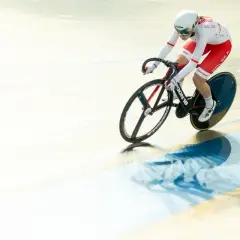 Kolarz w stroju z napisem POLSKA pędzi na torze kolarskim. To dynamiczne madison kolarstwo.