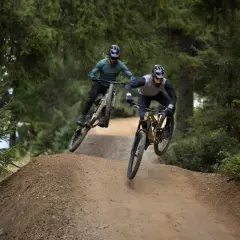 Dwóch rowerzystów w powietrzu na trasie zjazdowej. To właśnie **enduro co to** za sport, adrenalina i wolność!