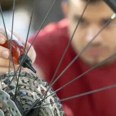 Mężczyzna aplikuje olej na łańcuch roweru, dbając o płynną jazdę. Smarowanie roweru to klucz do jego długowieczności.