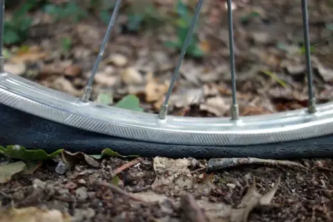 Płaska opona rowerowa leży na ziemi. Dowiedz się, jak napompować rower kompresorem, aby uniknąć takich sytuacji.
