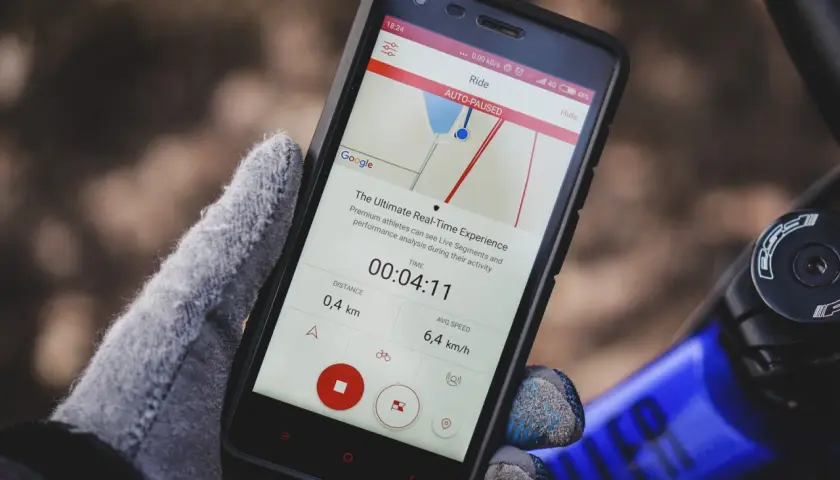 Rękawiczka trzyma smartfon z aplikacją do śledzenia aktywności. Szukasz co zamiast Endomondo? Ta aplikacja pokazuje dystans 0,4 km i średnią prędkość 6,4 km/h.