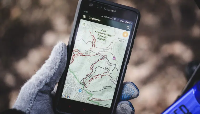 Rękawiczka trzyma smartfon z mapą szlaków rowerowych w Beskidzie Małym. To darmowa aplikacja do jazdy na rowerze, idealna na wyprawę.