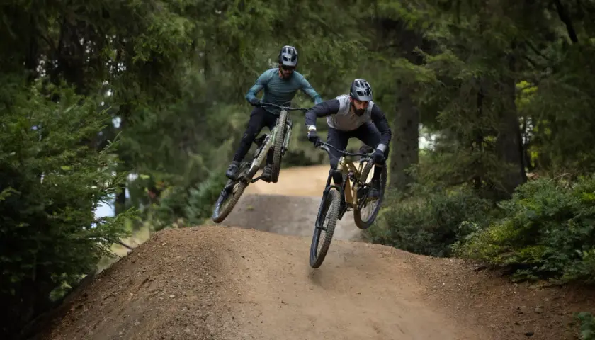 Dwóch rowerzystów w powietrzu na trasie zjazdowej. To właśnie **enduro co to** za sport, adrenalina i wolność!