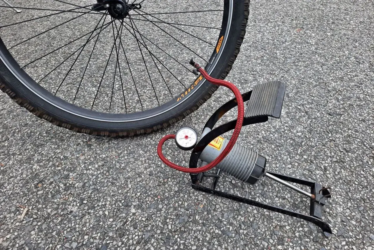 Pompka rowerowa z manometrem obok koła. Sprawdź ciśnienie w oponach rowerowych, tabela pomoże Ci dobrać odpowiednie.