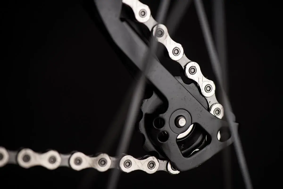 Zbliżenie na rowerowy napęd, gdzie widać mechanizm przerzutki i fragment łańcucha. Dowiedz się, jak liczyć ogniwa w łańcuchu, by zapewnić płynną jazdę.