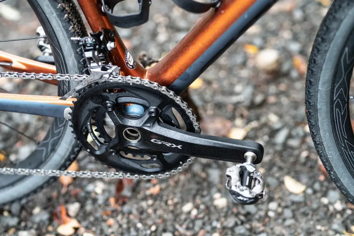 Naprawa napędu roweru gravelowego. Widoczny mechanizm korbowy GRX, łańcuch i pedał.