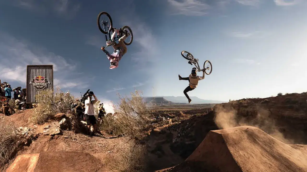 Dwóch kolarzy wykonuje ewolucje w powietrzu podczas Red Bull Rampage. Jeden z nich robi salto w tył, drugi jest w trakcie akrobacji.