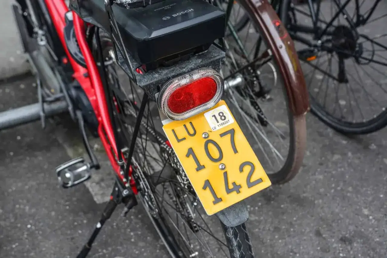 Czerwony rower z tablicą rejestracyjną LU 107 142. Bateria Bosch na bagażniku.
