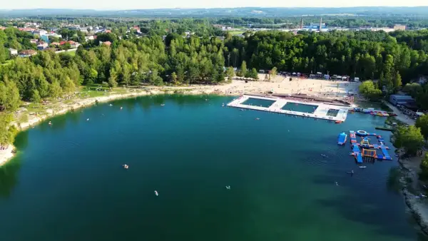 Letni dzień nad wodą w Trzebini. Ludzie odpoczywają na plaży i pływają w jeziorze, które przypomina Balaton.